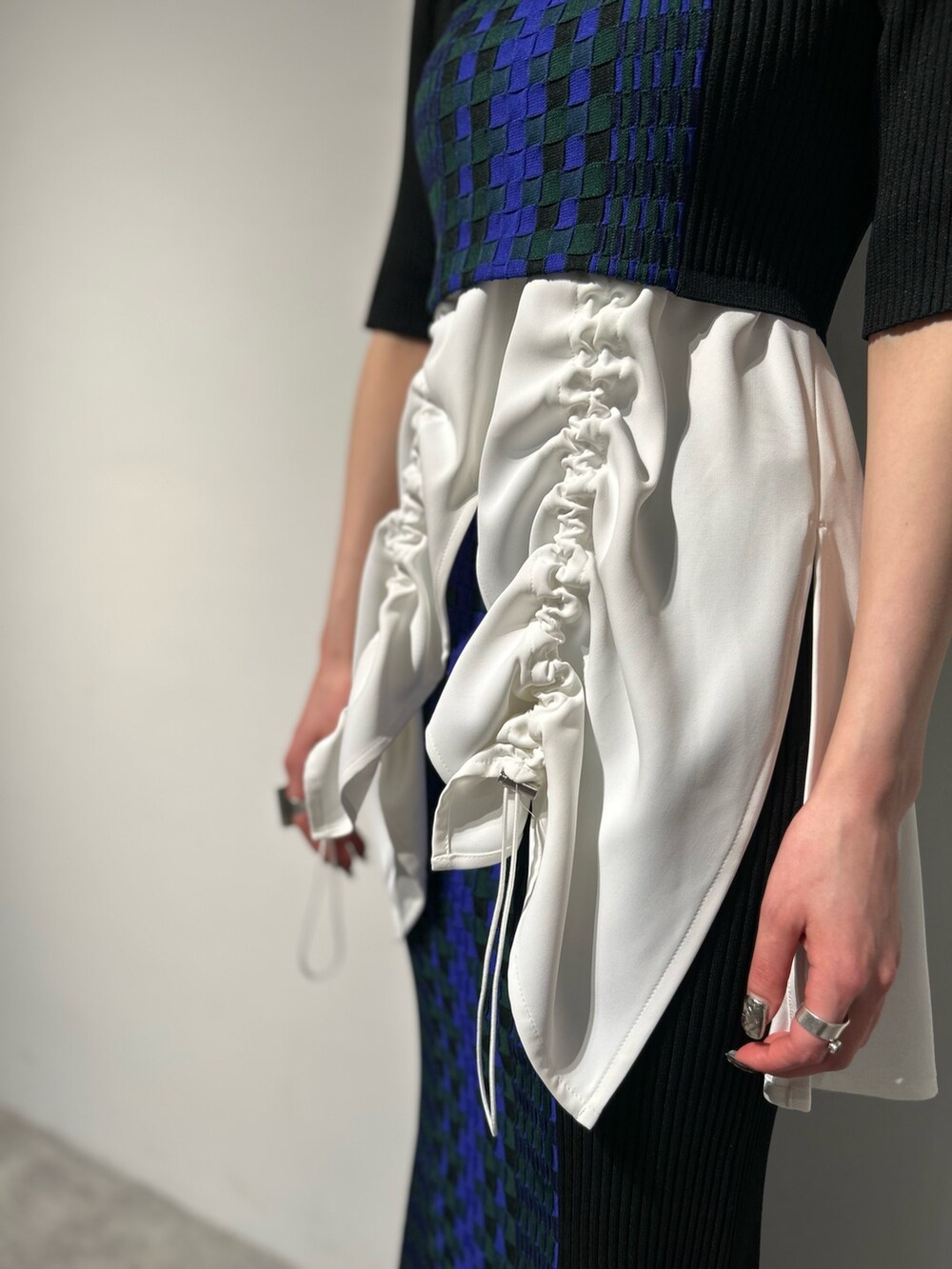 シルバー系のブーツ、ブラック系のスカート、ホワイト系のタンクトップを着用したレディースの冬コーディネートの7枚目の写真