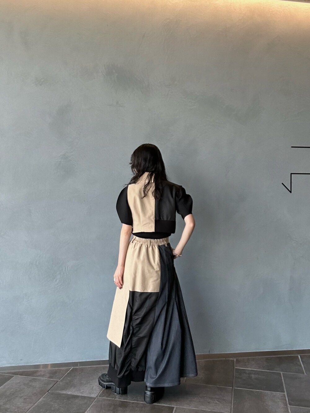 ベージュ系のスカート、ベージュ系のベスト、ブラック系のニット/セーターを着用したレディースの夏コーディネートの2枚目の写真