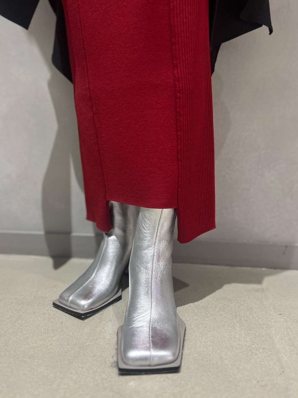 ブラック系のワンピース、レッド系のスカート、シルバー系のブーツを着用したレディースの冬コーディネートの10枚目の写真