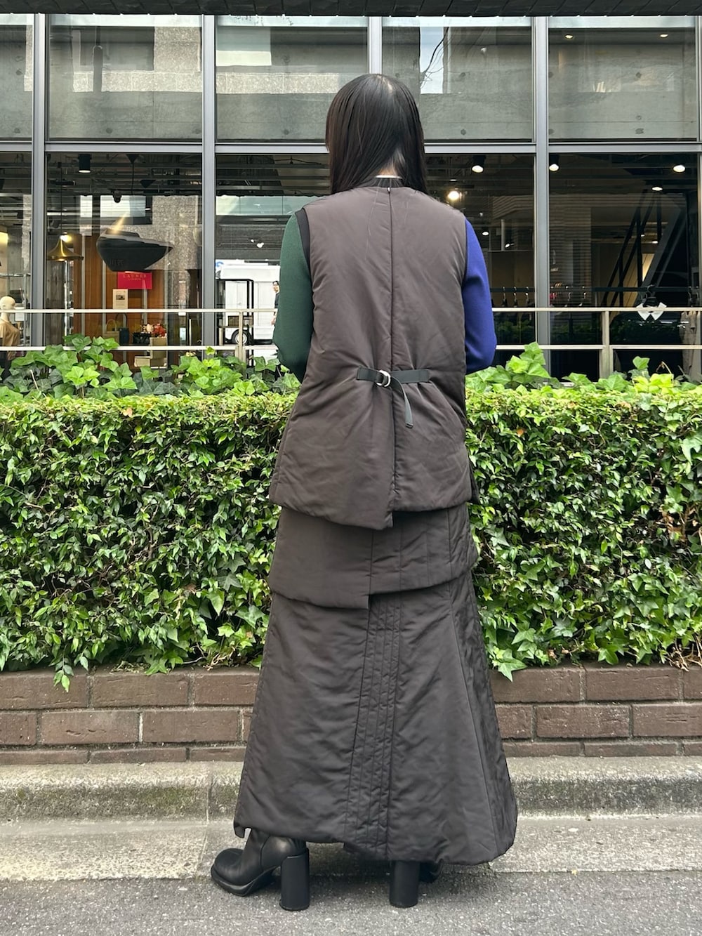 ブラック系のニット/セーター、ブラック系のスカート、ブラック系のダウンベストを着用したレディースの夏コーディネートの3枚目の写真