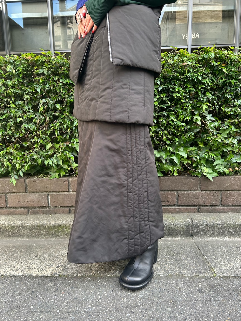 ブラック系のニット/セーター、ブラック系のスカート、ブラック系のダウンベストを着用したレディースの夏コーディネートの6枚目の写真