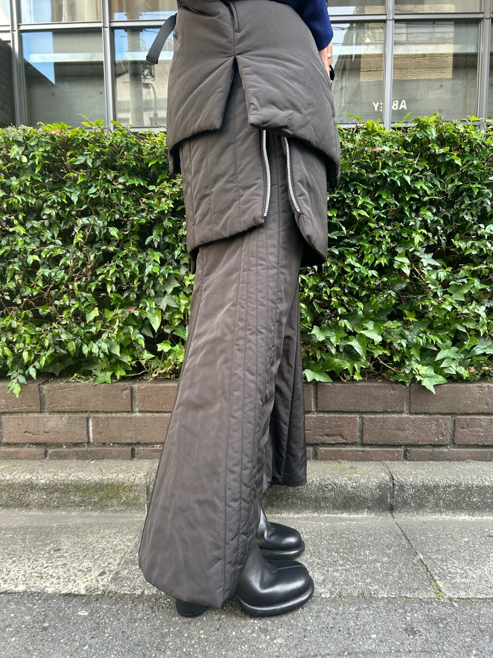 ブラック系のニット/セーター、ブラック系のスカート、ブラック系のダウンベストを着用したレディースの夏コーディネートの7枚目の写真