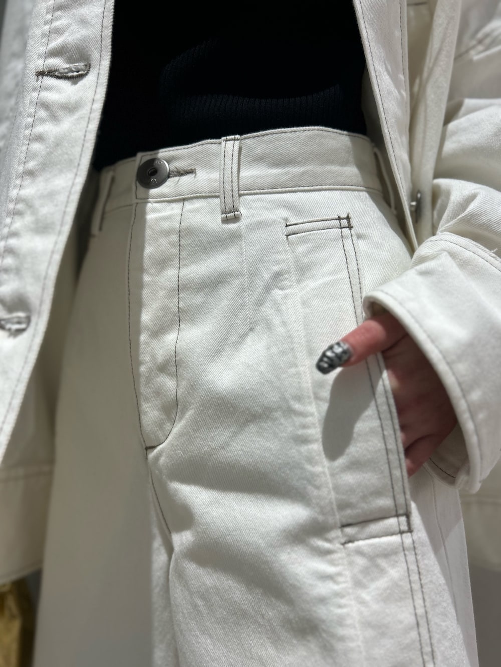 ホワイト系のデニムパンツ、ホワイト系のデニムジャケット、ブラック系のニット/セーターを着用したレディースの春コーディネートの8枚目の写真