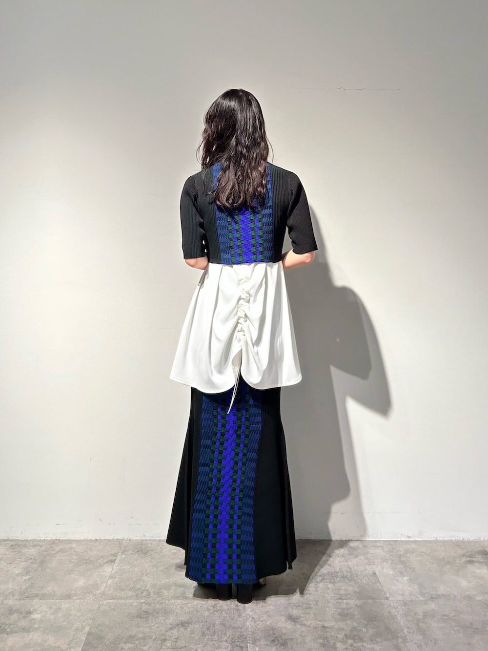 シルバー系のブーツ、ブラック系のスカート、ホワイト系のタンクトップを着用したレディースの冬コーディネートの2枚目の写真