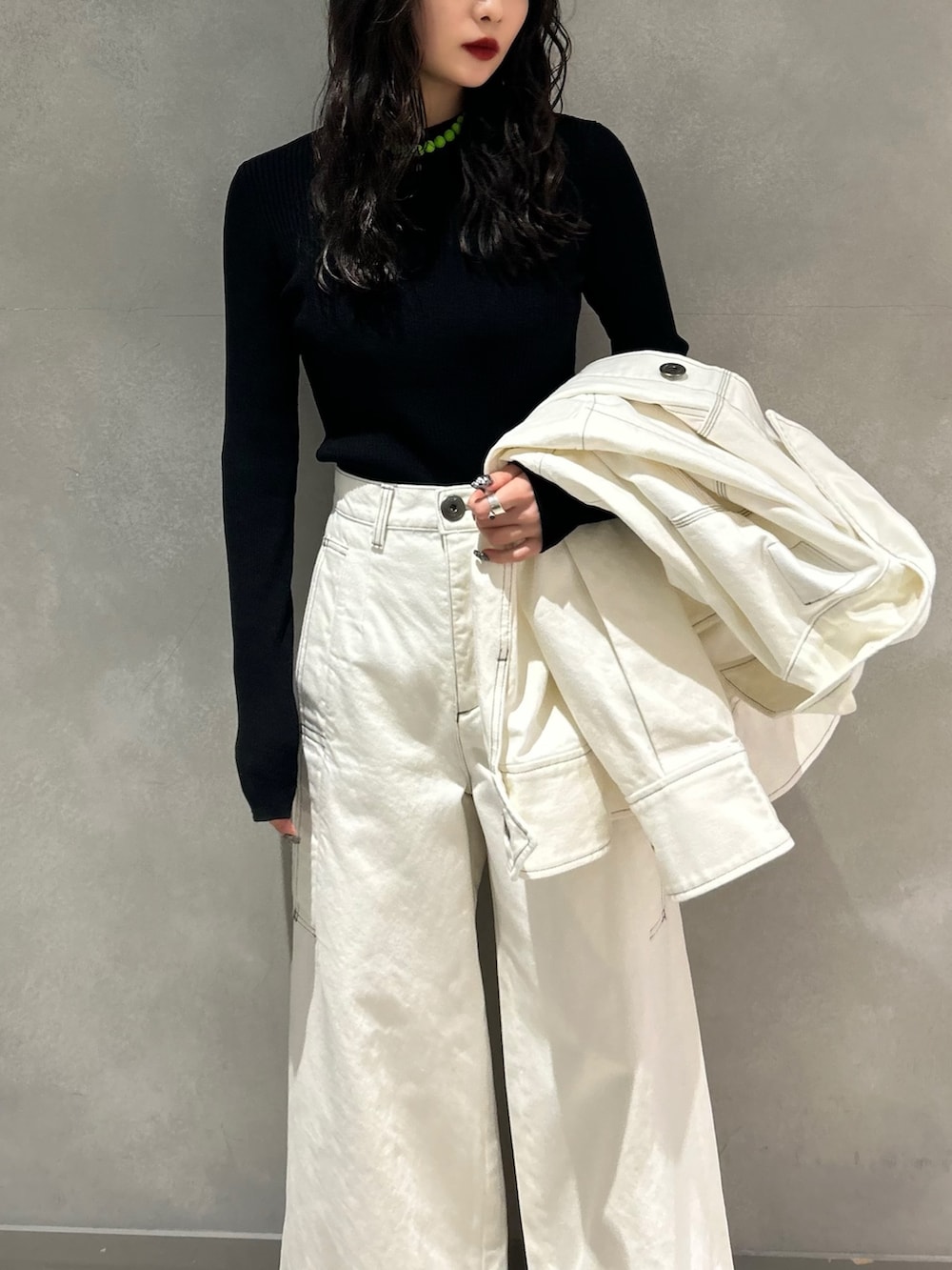 ホワイト系のデニムパンツ、ホワイト系のデニムジャケット、ブラック系のニット/セーターを着用したレディースの春コーディネートの4枚目の写真