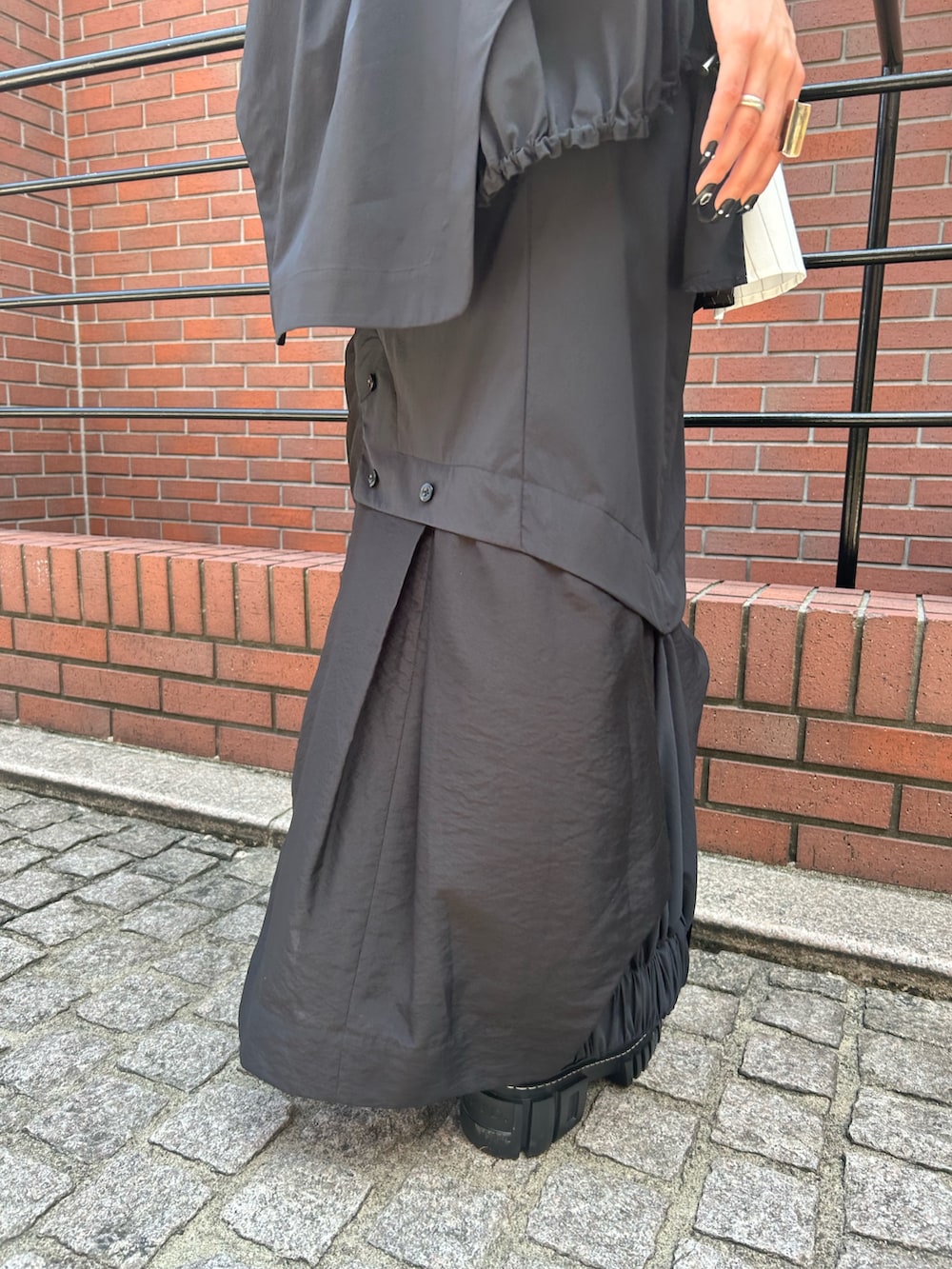 ブラック系のスカート、ブラック系のTシャツ/カットソー、ブラック系のブーツを着用したレディースの夏コーディネートの7枚目の写真