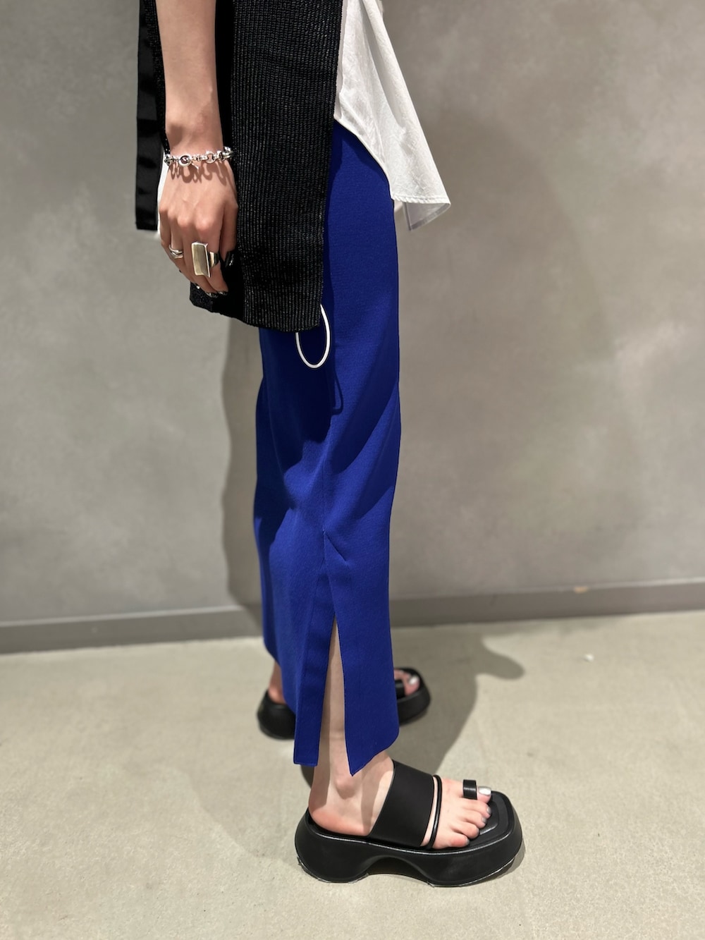 ブラック系のベスト、ホワイト系のシャツ/ブラウス、ブルー系のスカートを着用したレディースの夏コーディネートの6枚目の写真