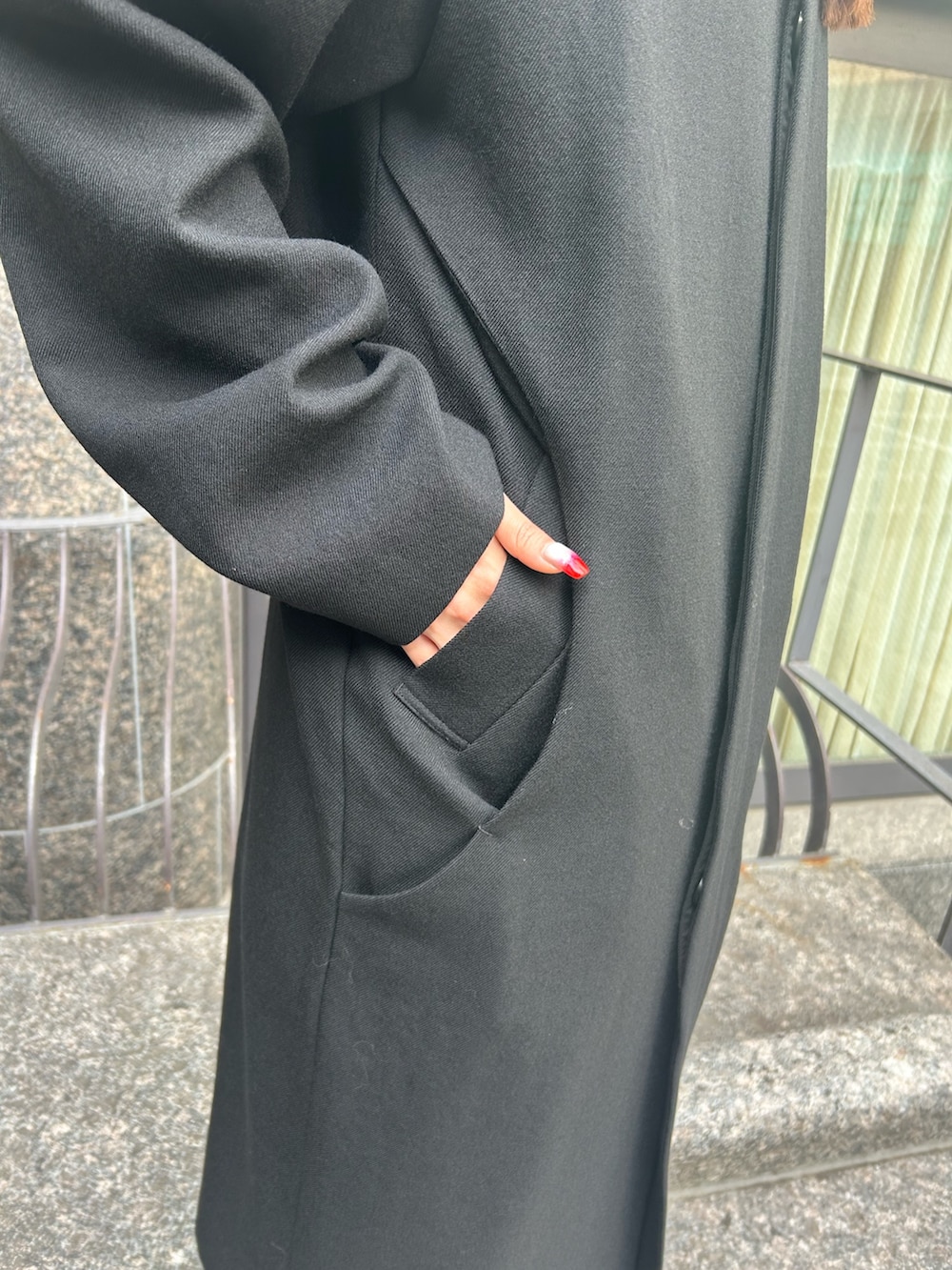 ブラック系のステンカラーコート、ブラック系のブーツを着用したレディースの秋コーディネートの6枚目の写真