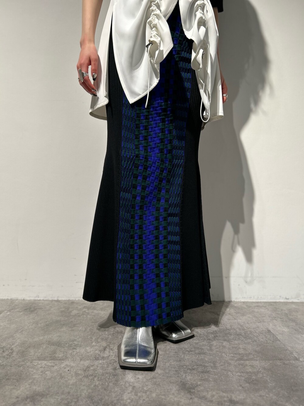 シルバー系のブーツ、ブラック系のスカート、ホワイト系のタンクトップを着用したレディースの冬コーディネートの9枚目の写真