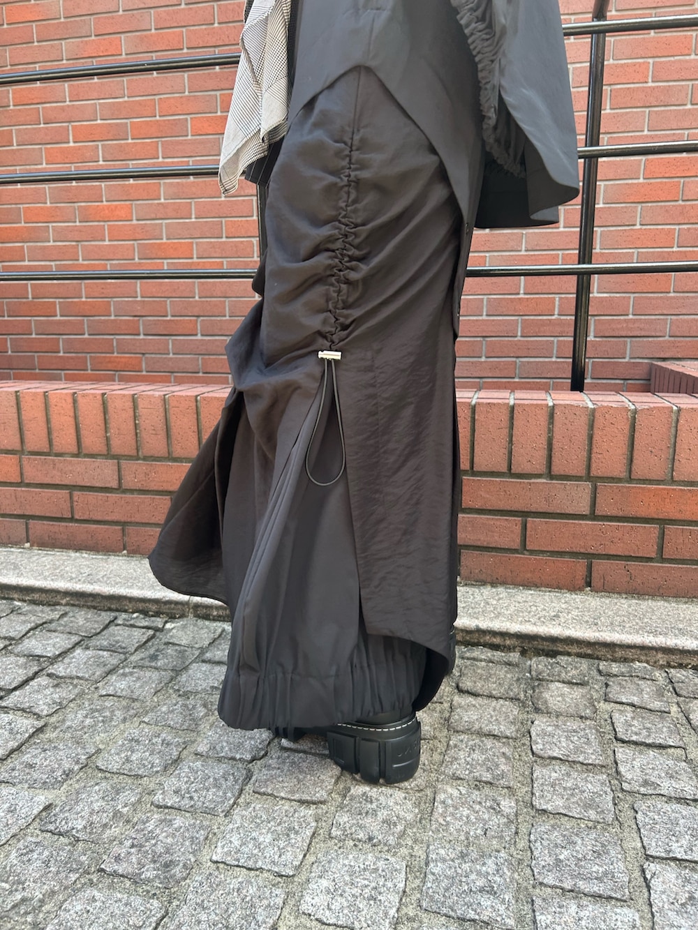 ブラック系のスカート、ブラック系のTシャツ/カットソー、ブラック系のブーツを着用したレディースの夏コーディネートの9枚目の写真