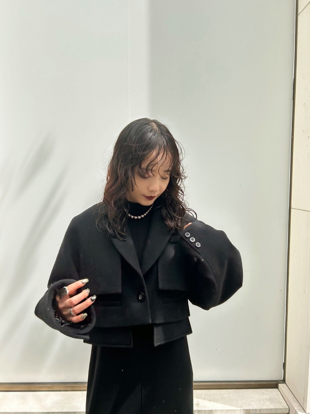 グレー系のテーラードジャケット、ホワイト系のワンピース、ブラック系のパンプスを着用したレディースの夏コーディネートの3枚目の写真