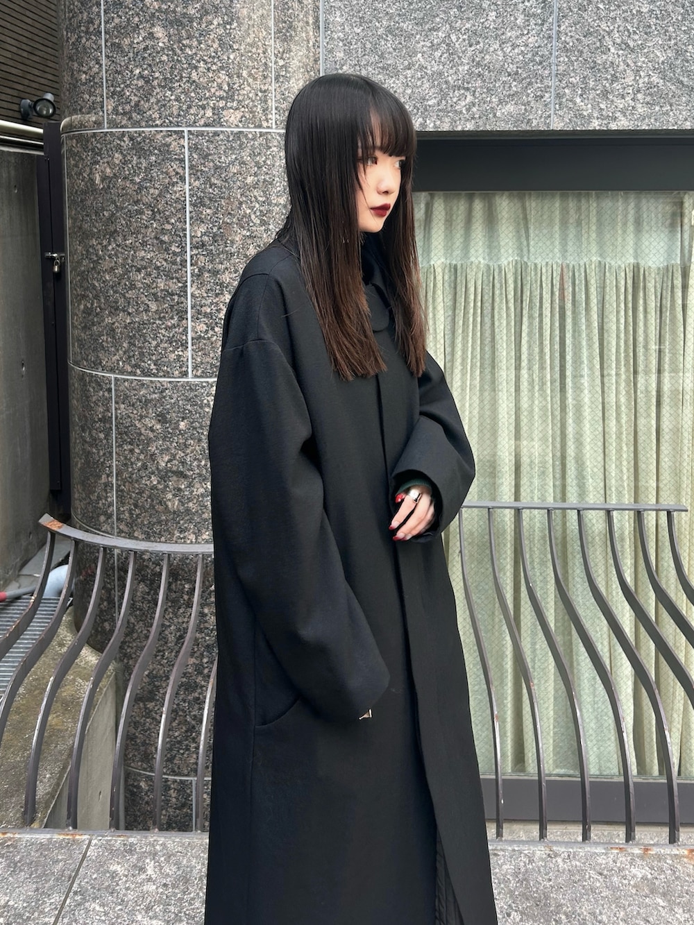 ブラック系のステンカラーコート、ブラック系のブーツを着用したレディースの秋コーディネートの2枚目の写真