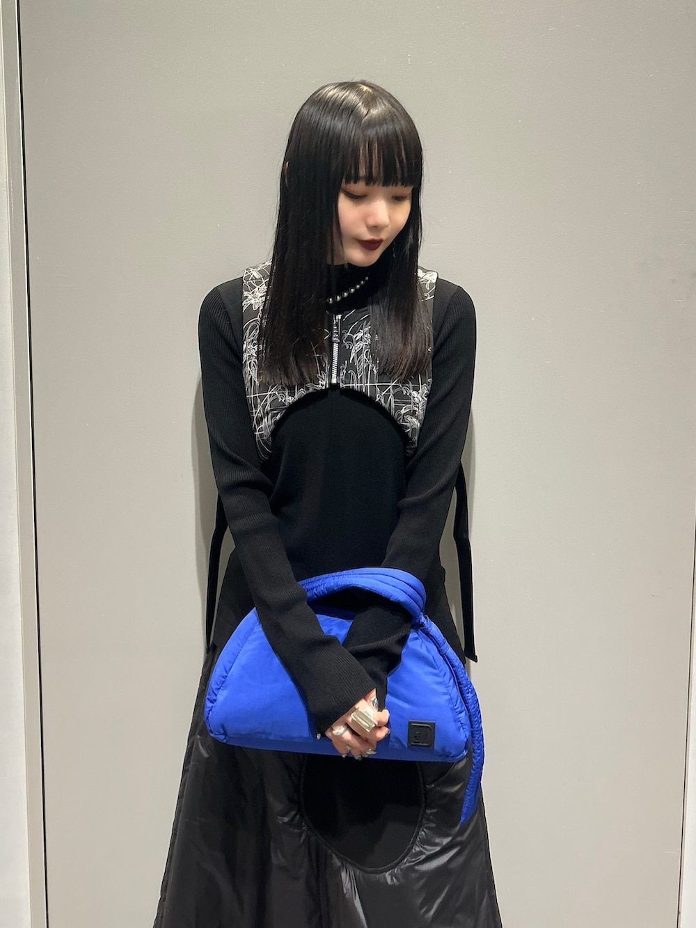 ブラック系のニット/セーター、ブラック系のベスト、ブルー系のハンドバッグを着用したレディースの秋コーディネートの4枚目の写真