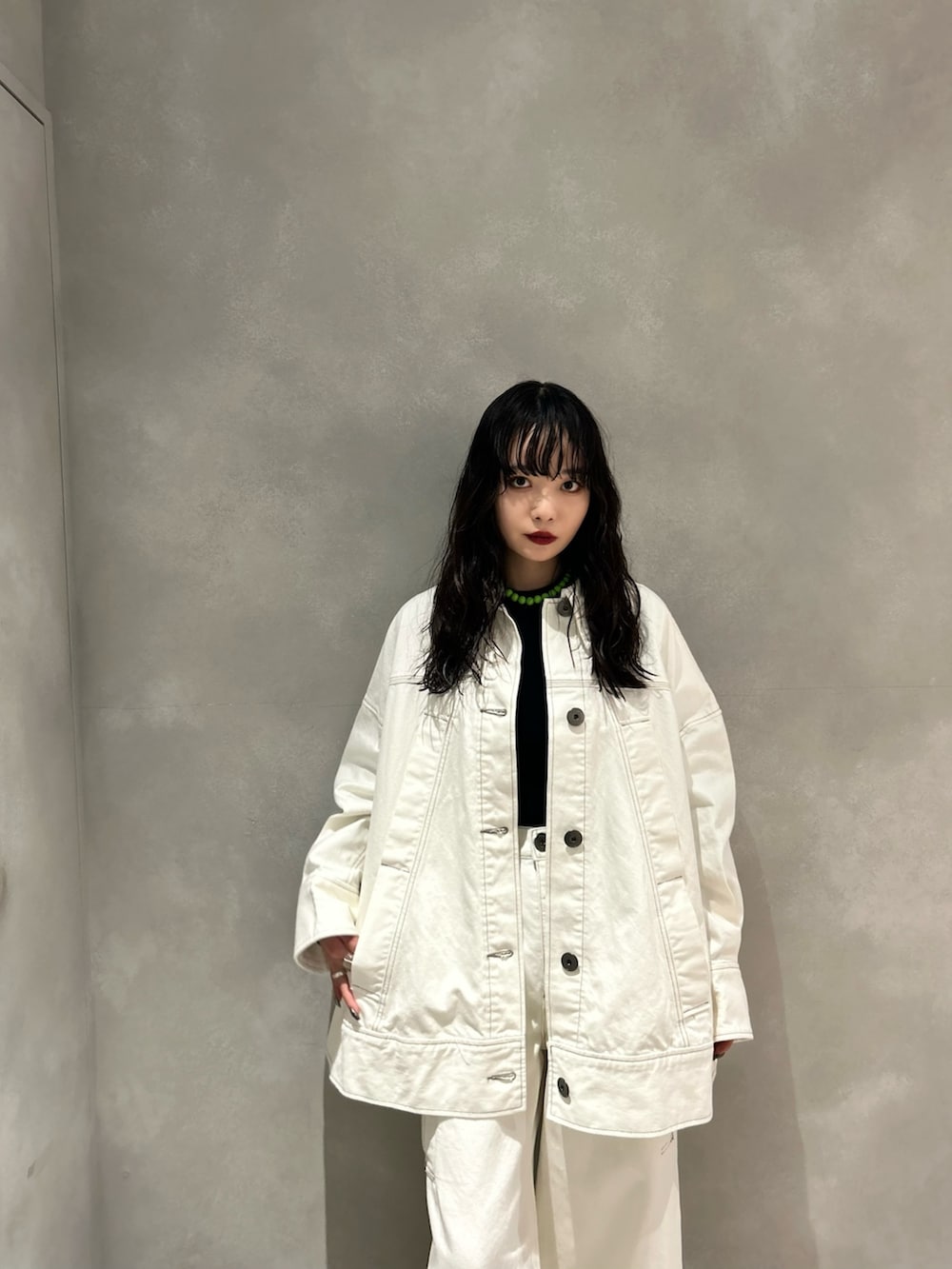 ホワイト系のデニムパンツ、ホワイト系のデニムジャケット、ブラック系のニット/セーターを着用したレディースの春コーディネートの2枚目の写真