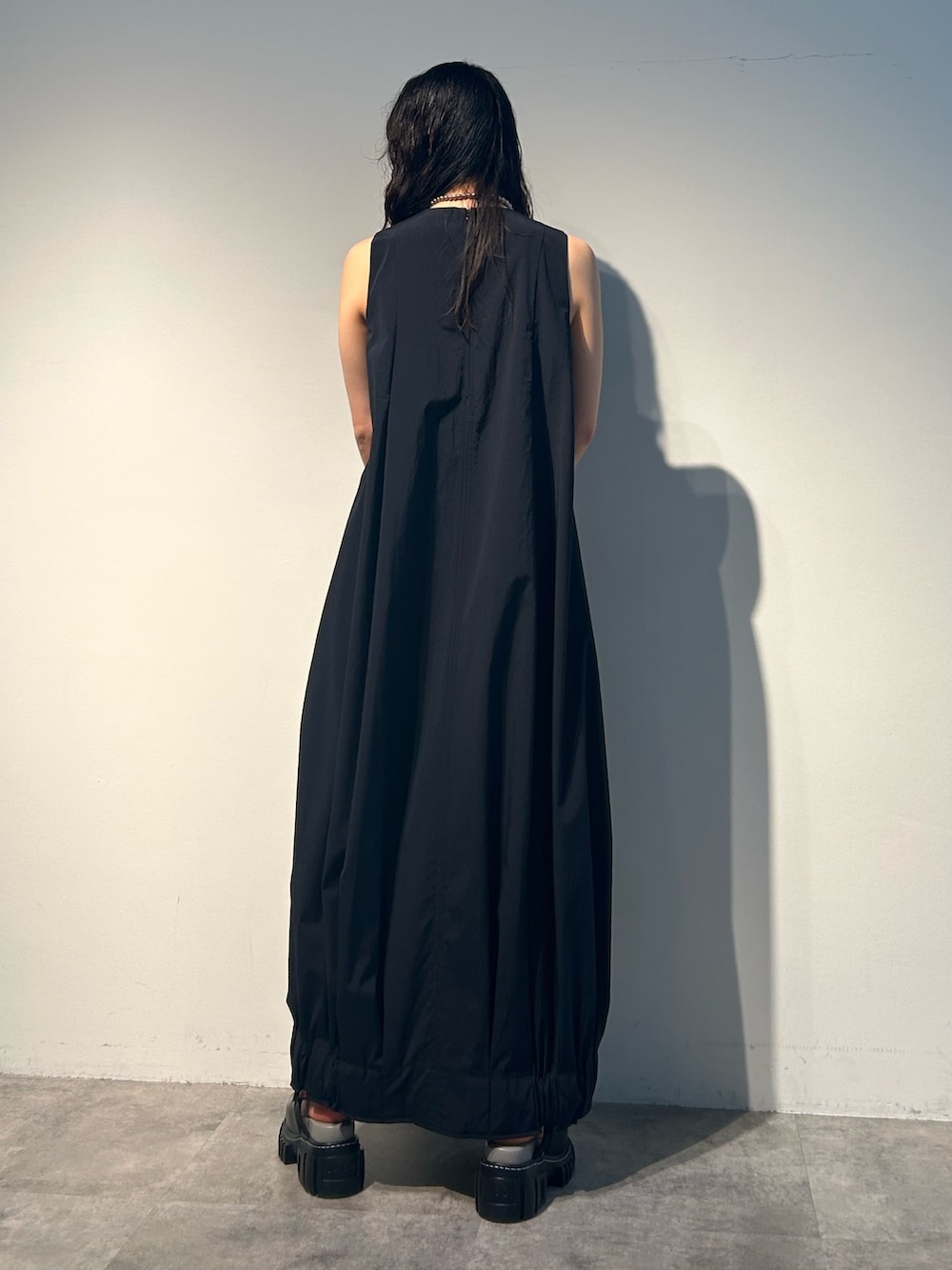 ブラック系のワンピース、グリーン系のトートバッグ、その他のサンダルを着用したレディースの夏コーディネートの2枚目の写真