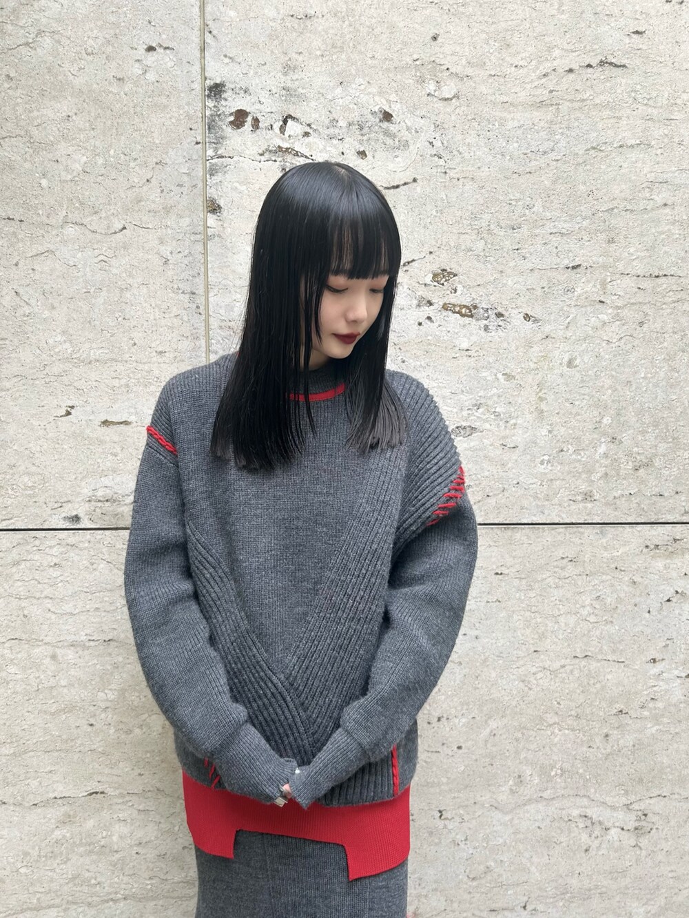 グレー系のスカート、グレー系のニット/セーター、シルバー系のブーツを着用したレディースの秋コーディネートの2枚目の写真