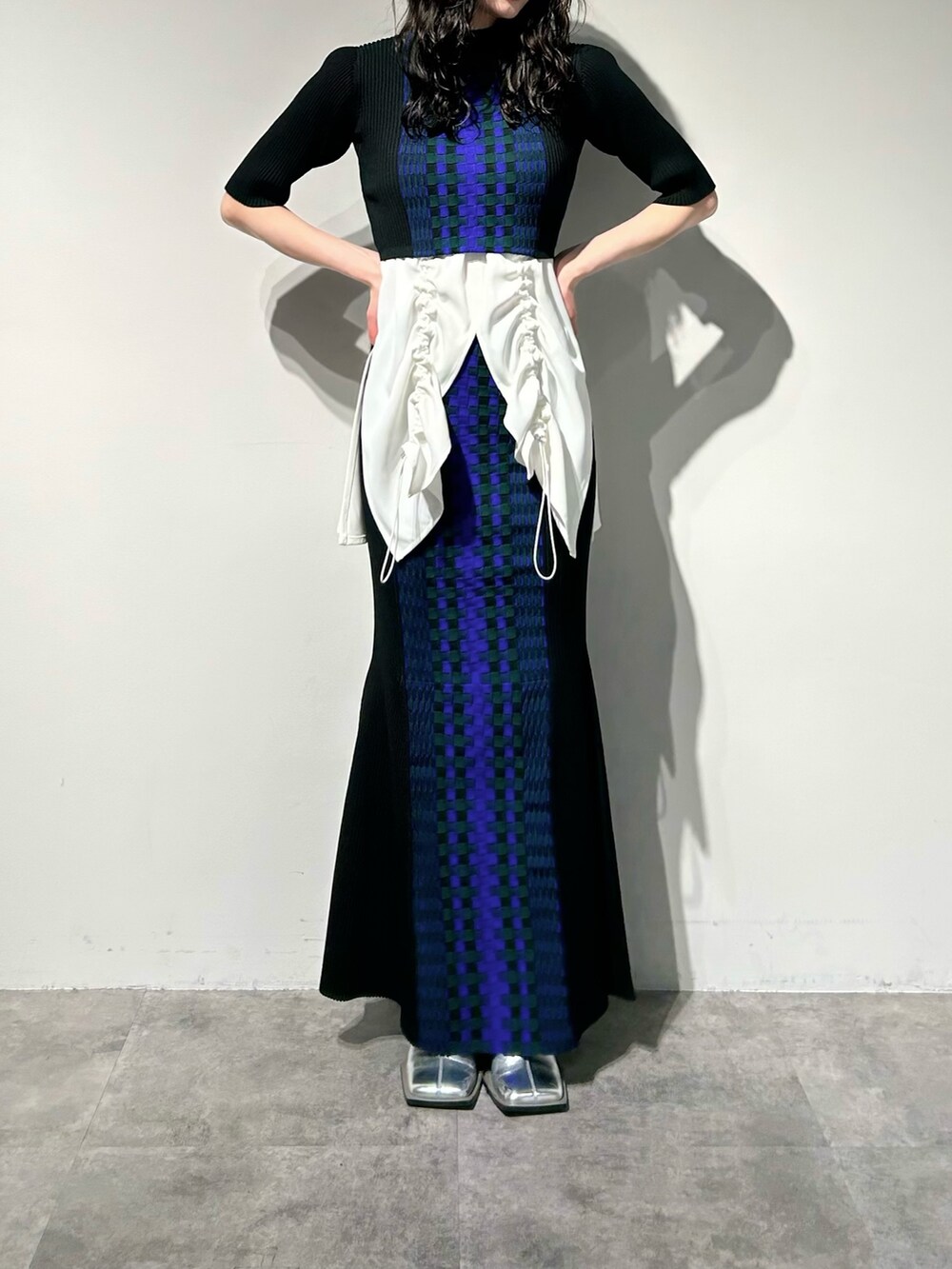 シルバー系のブーツ、ブラック系のスカート、ホワイト系のタンクトップを着用したレディースの冬コーディネートの4枚目の写真