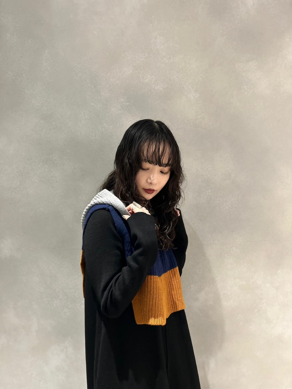 ブラック系のワンピース、ブラック系のブーツ、グレー系のネックウォーマー/スヌードを着用したレディースの冬コーディネートの3枚目の写真