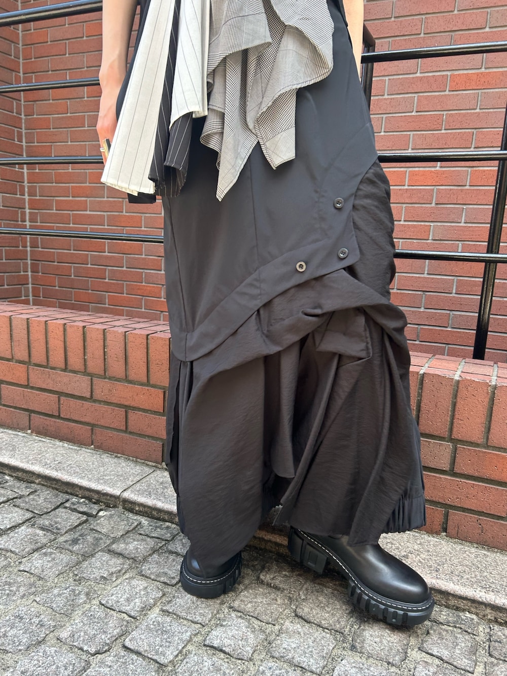 ブラック系のスカート、ブラック系のTシャツ/カットソー、ブラック系のブーツを着用したレディースの夏コーディネートの6枚目の写真