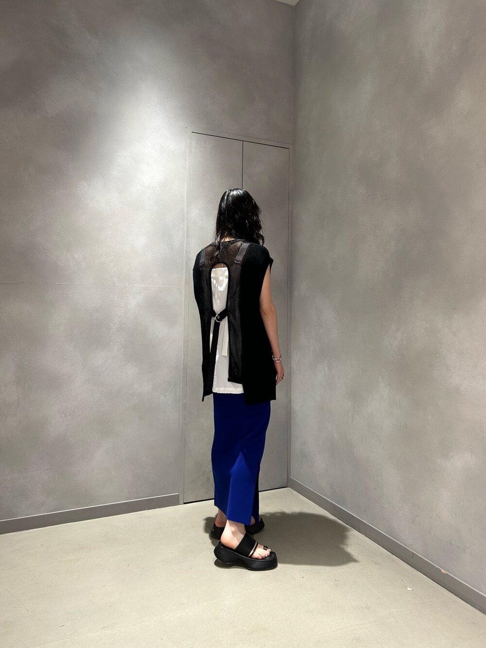 ブラック系のベスト、ホワイト系のシャツ/ブラウス、ブルー系のスカートを着用したレディースの夏コーディネートの3枚目の写真