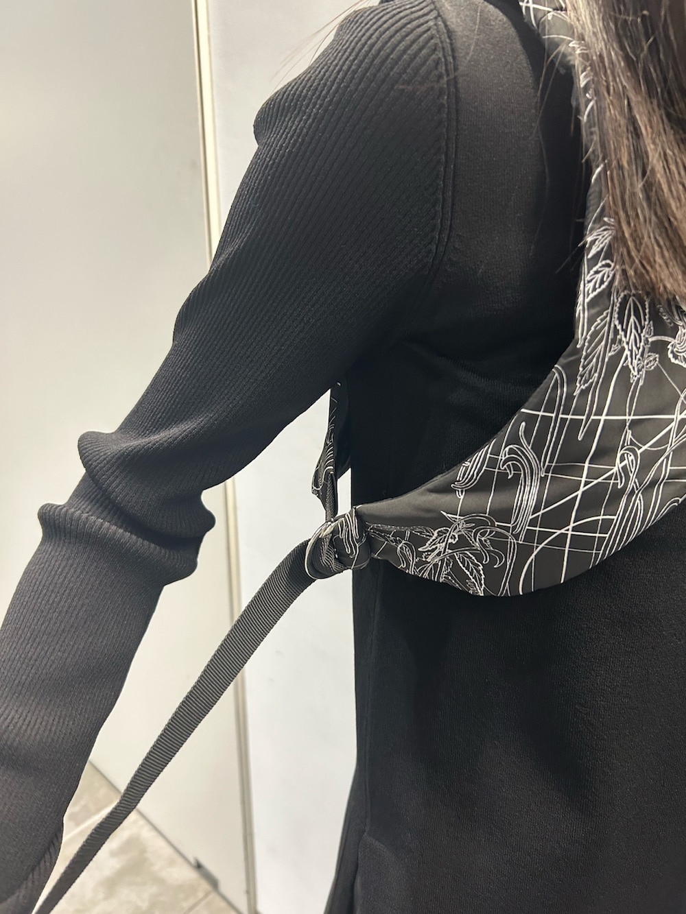 ブラック系のニット/セーター、ブラック系のベスト、ブルー系のハンドバッグを着用したレディースの秋コーディネートの7枚目の写真