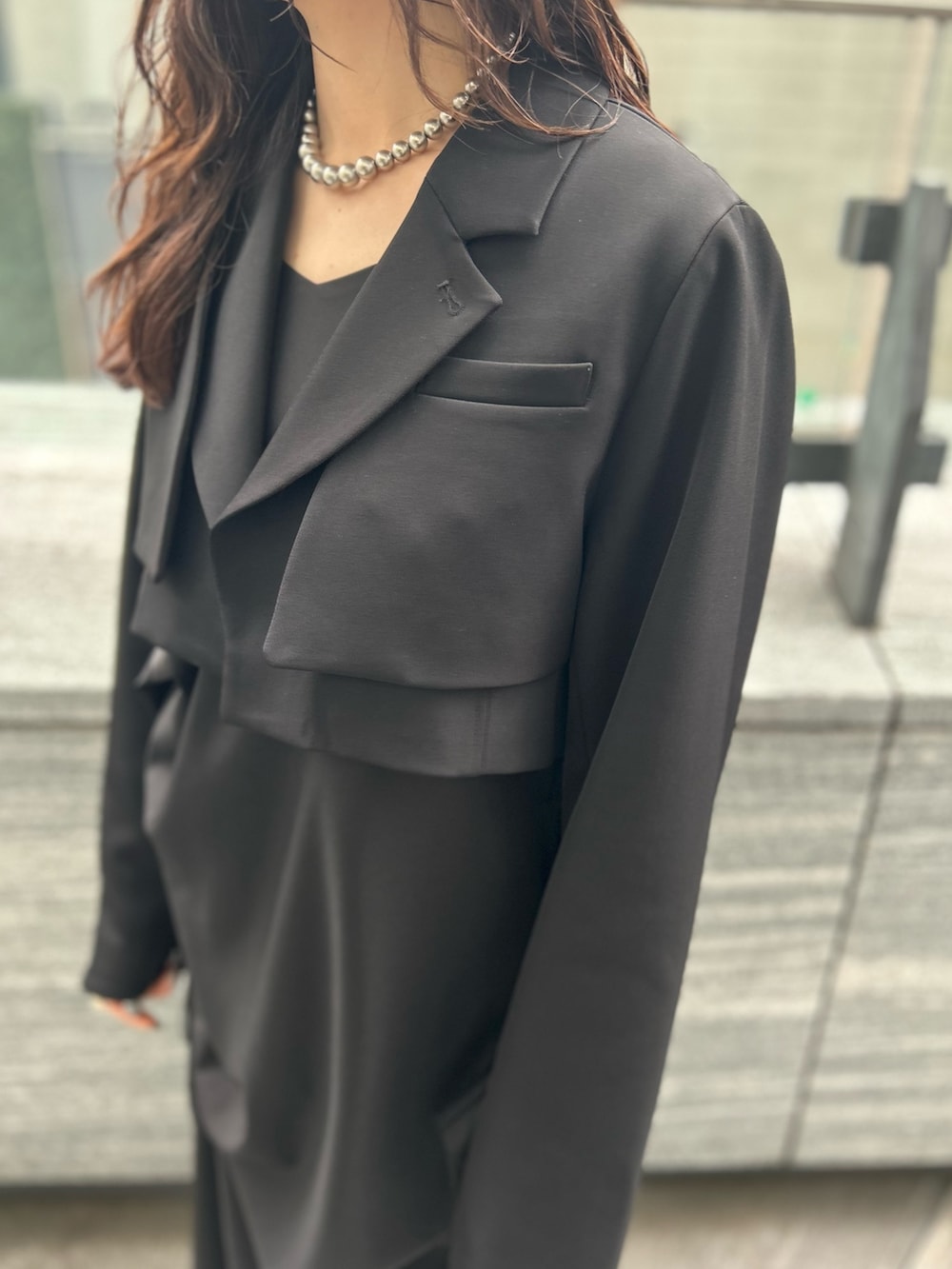 ブラック系のワンピース、ブラック系のテーラードジャケット、シルバー系のブーツを着用したレディースの春コーディネートの5枚目の写真