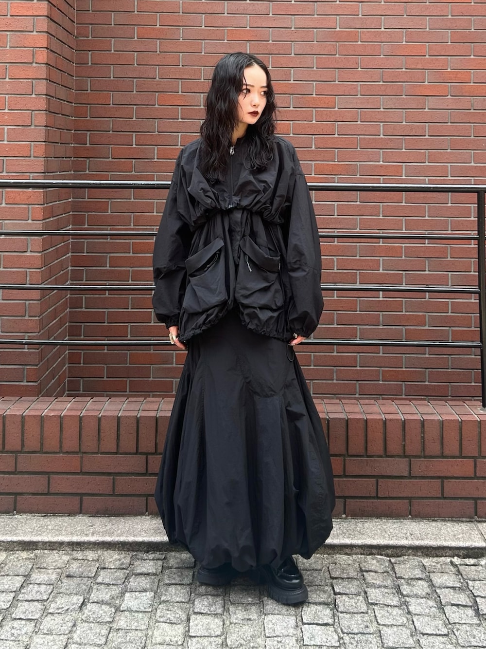 ブラック系のブルゾン、ブラック系のスカートを着用したレディースの夏コーディネートの2枚目の写真
