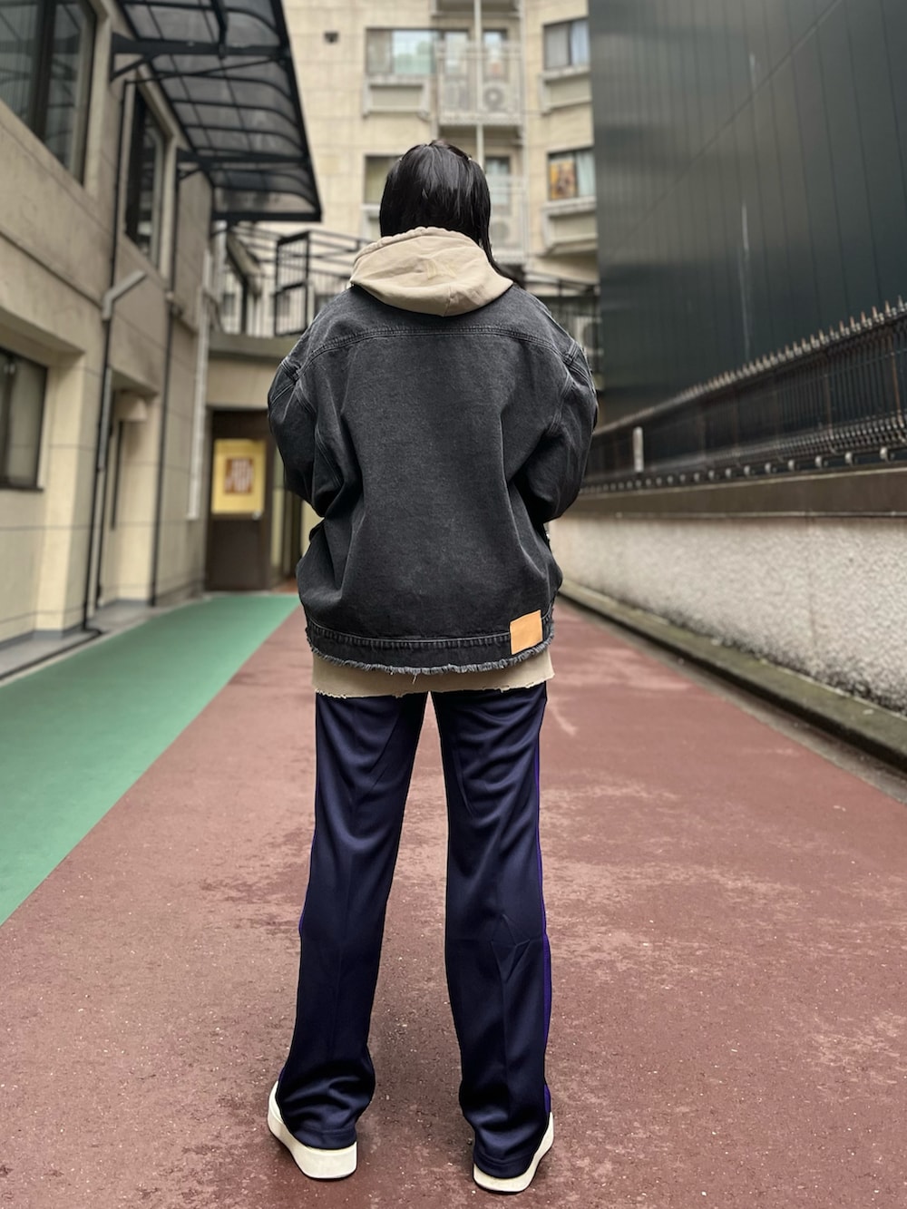 ブラック系のデニムジャケット、パープル系のパンツ、ベージュ系のパーカーを着用したレディースの冬コーディネートの3枚目の写真