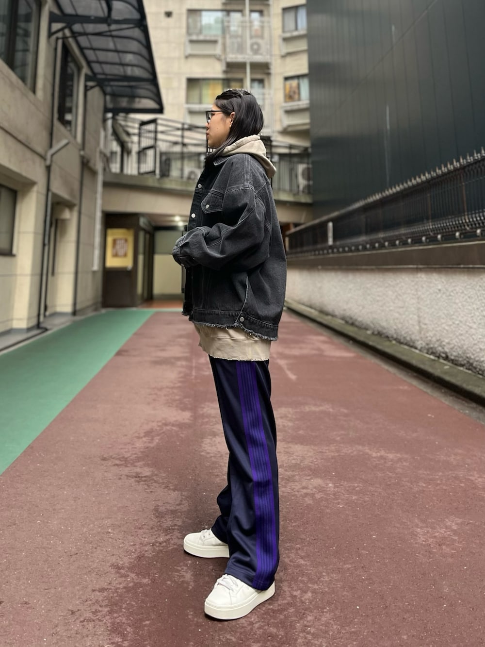 ブラック系のデニムジャケット、パープル系のパンツ、ベージュ系のパーカーを着用したレディースの冬コーディネートの2枚目の写真