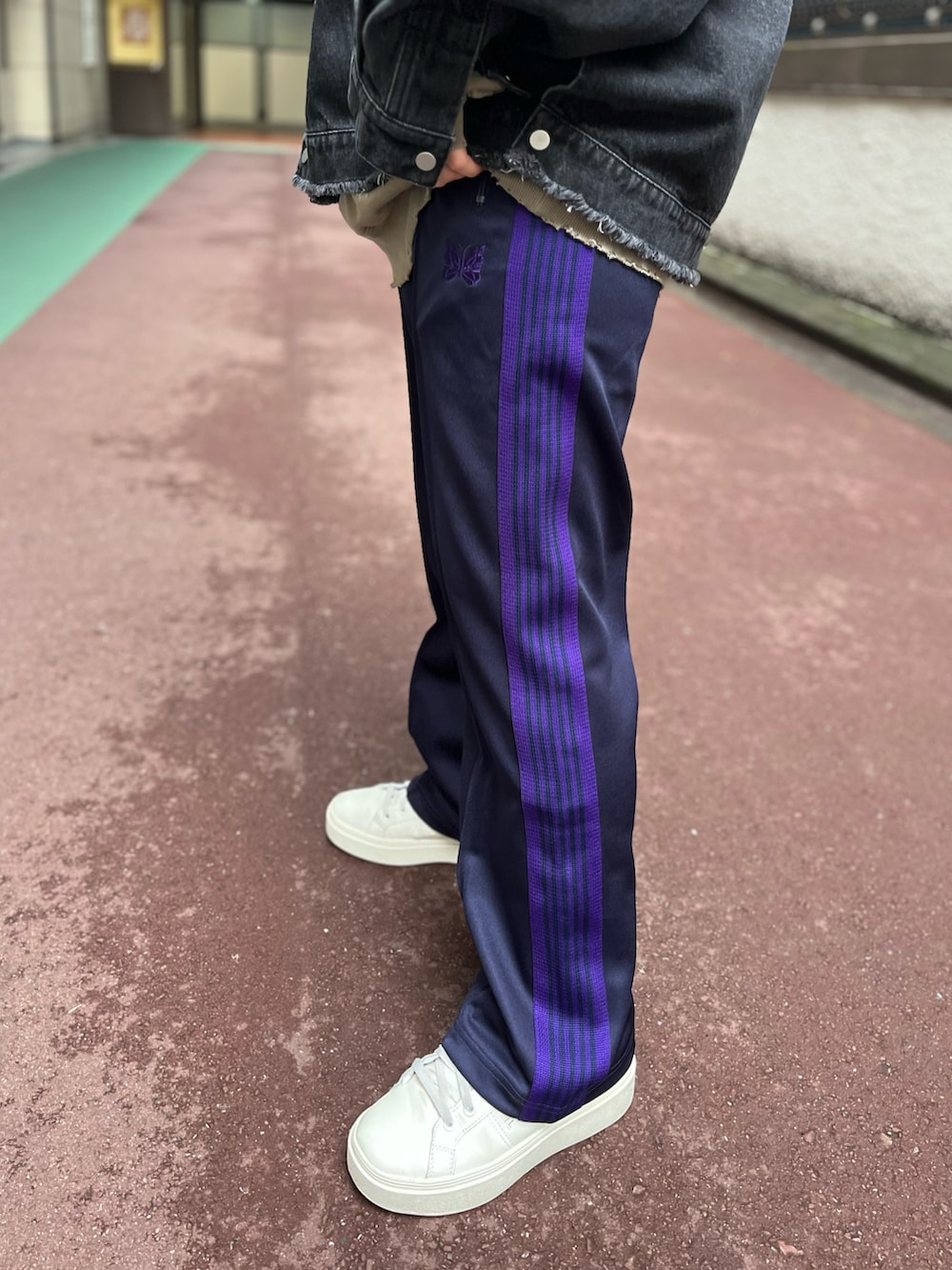 ブラック系のデニムジャケット、パープル系のパンツ、ベージュ系のパーカーを着用したレディースの冬コーディネートの4枚目の写真