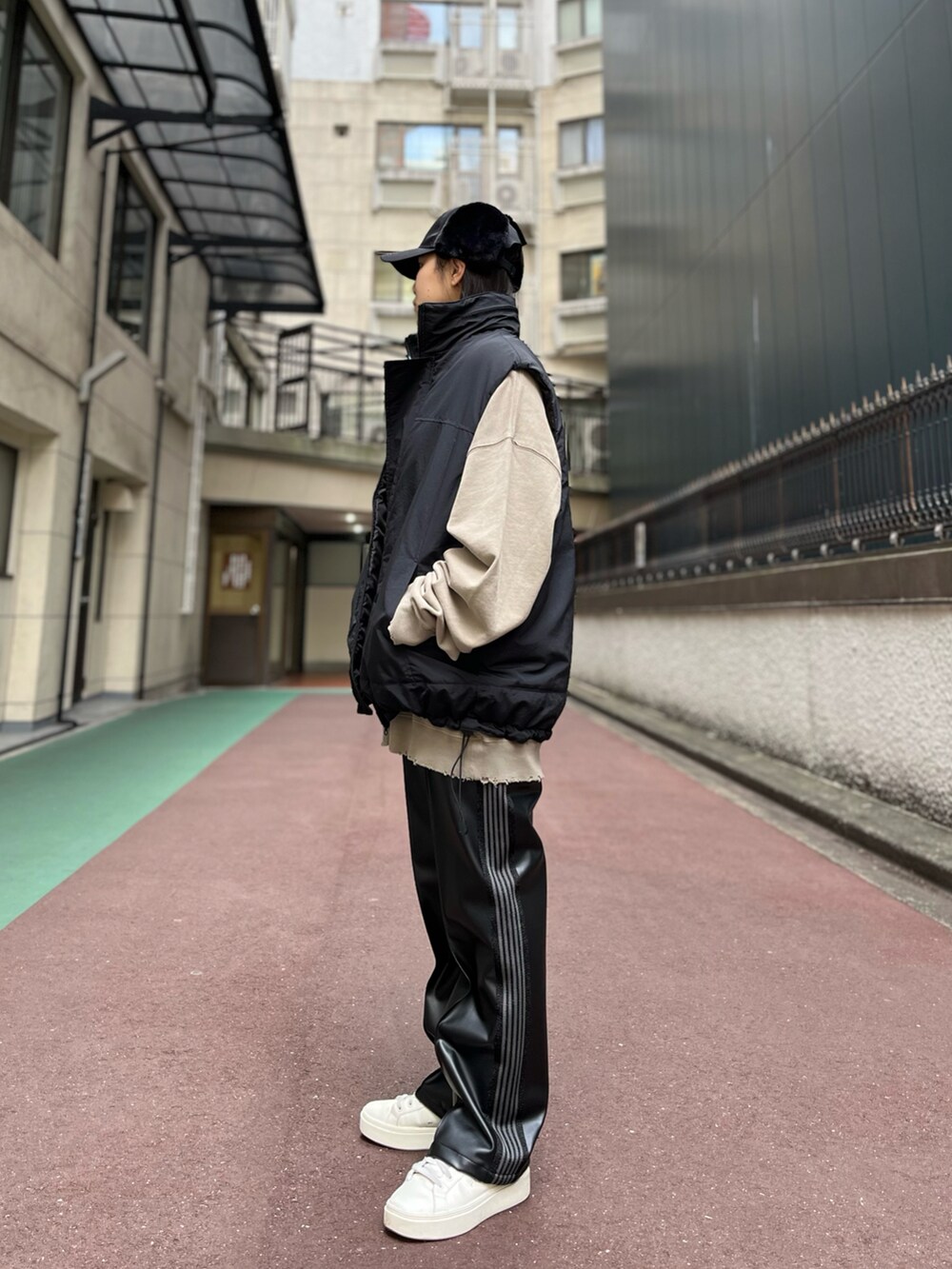 ブラック系のダウンベスト、パープル系のパンツ、ベージュ系のスウェットを着用したレディースの冬コーディネートの2枚目の写真