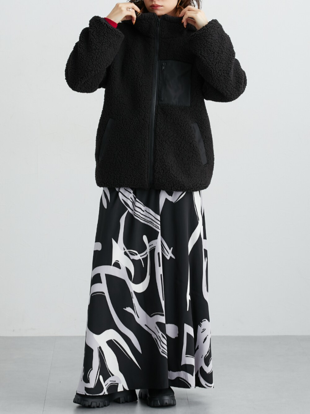 ブラック系のスカート、レッド系のニット/セーター、ブラック系のカバーオールを着用したレディースの秋コーディネートの2枚目の写真