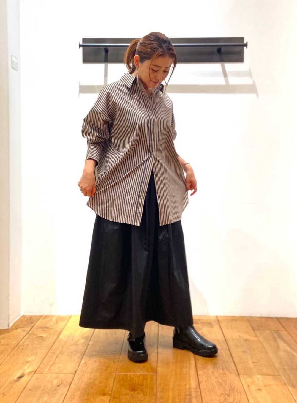 ブラック系のブーツ、グレー系のシャツ/ブラウス、ブラック系のスカートを着用したレディースの秋コーディネートの2枚目の写真