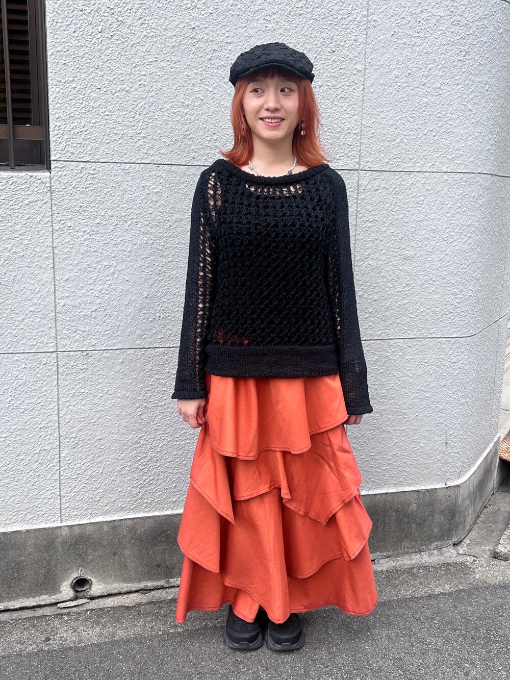 ブラック系のニット/セーター、オレンジ系のスカート、ブラック系のハンチング/ベレー帽を着用したレディースの夏コーディネートの4枚目の写真