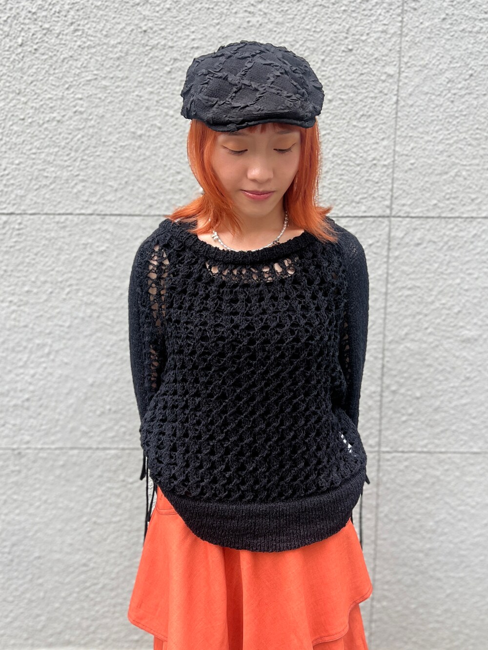 ブラック系のニット/セーター、オレンジ系のスカート、ブラック系のハンチング/ベレー帽を着用したレディースの夏コーディネートの5枚目の写真