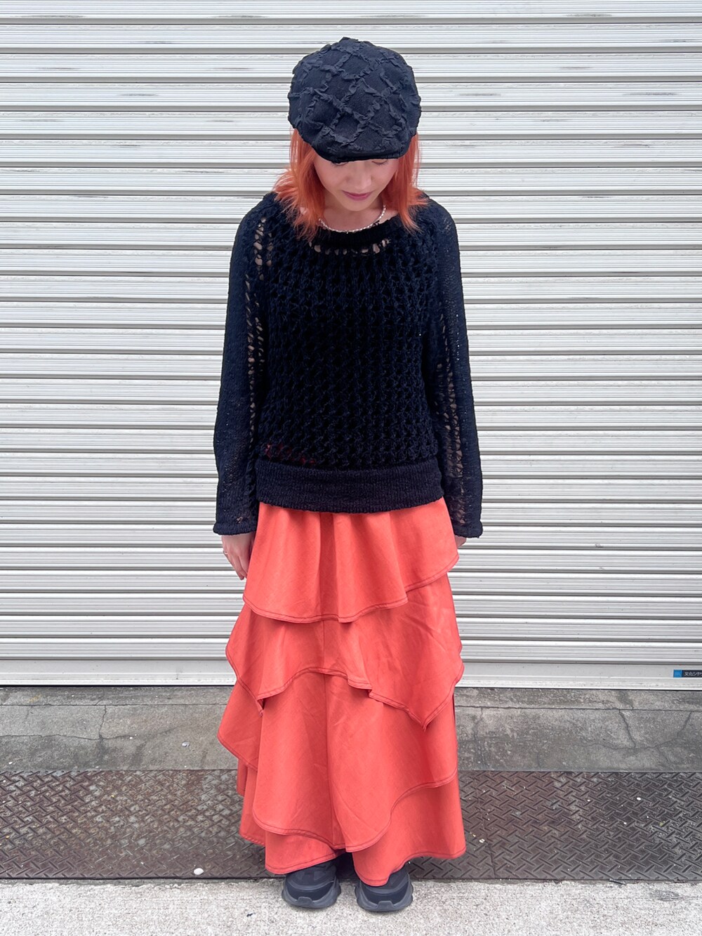 ブラック系のニット/セーター、オレンジ系のスカート、ブラック系のハンチング/ベレー帽を着用したレディースの夏コーディネートの2枚目の写真