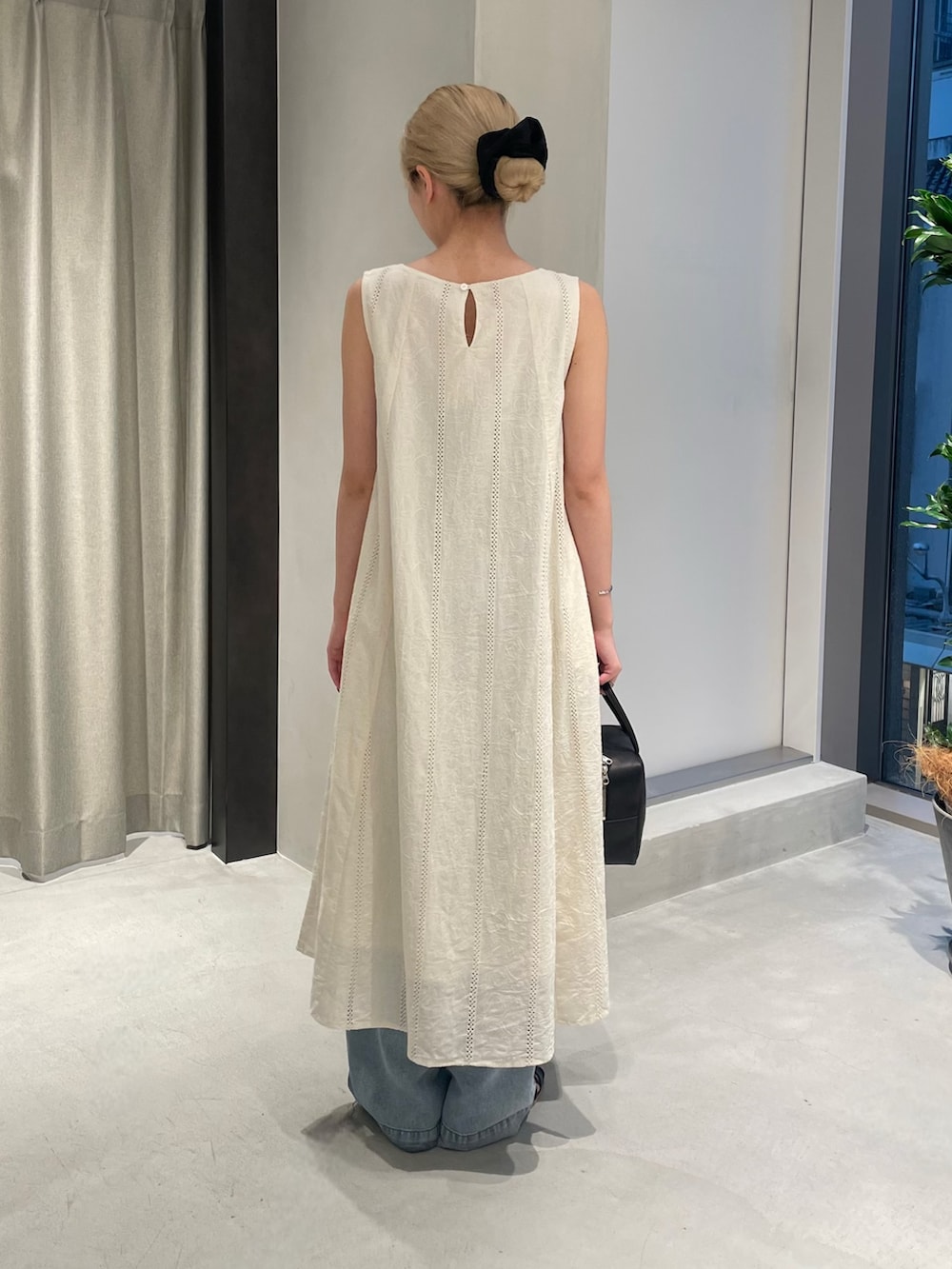 ブルー系のデニムパンツ、ブラック系のサンダル、ブラック系のボストンバッグを着用したレディースの夏コーディネートの5枚目の写真