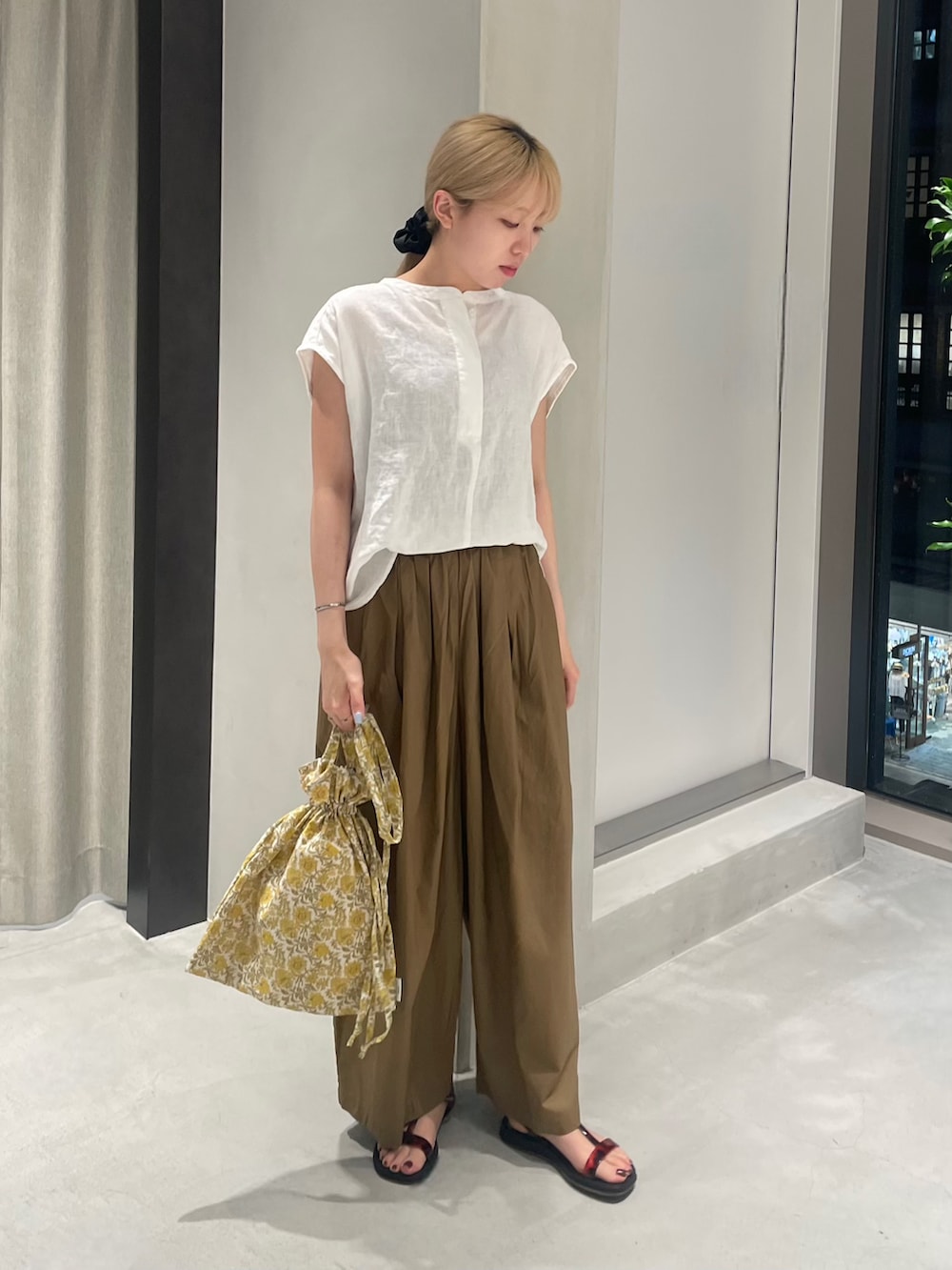 イエロー系のトートバッグ、ベージュ系のその他パンツ、ホワイト系のシャツ/ブラウスを着用したレディースの夏コーディネートの2枚目の写真