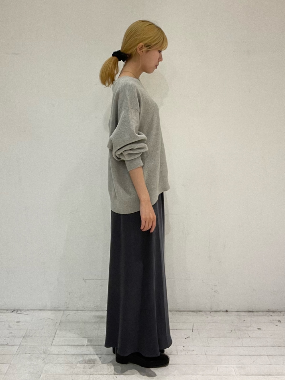 グレー系のスカート、ブラック系のブーツ、ブラック系のショルダーバッグを着用したレディースの秋コーディネートの3枚目の写真