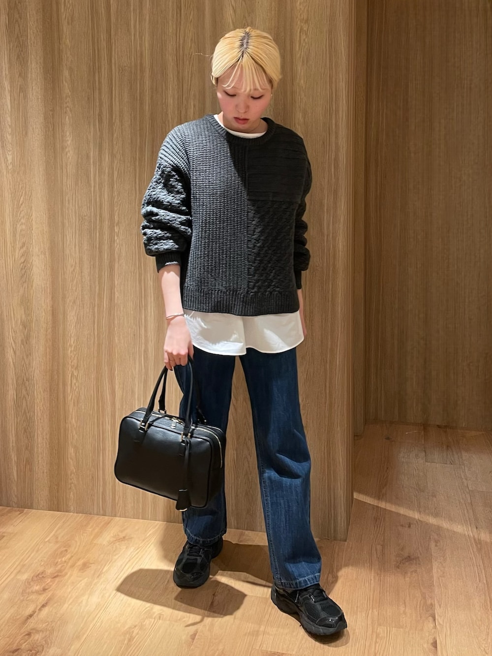 ブラック系のスニーカー、ブルー系のデニムパンツ、ブラック系のボストンバッグを着用したレディースの冬コーディネートの5枚目の写真