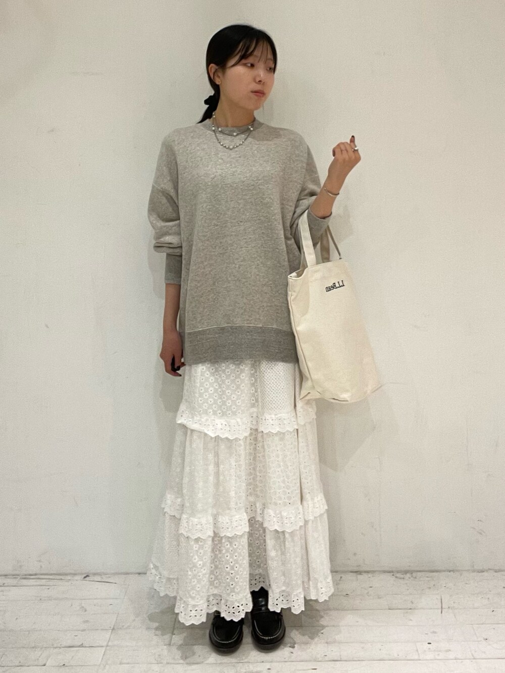 ベージュ系のショルダーバッグ、ホワイト系のスカート、ブラック系のローファーを着用したレディースの秋コーディネートの2枚目の写真