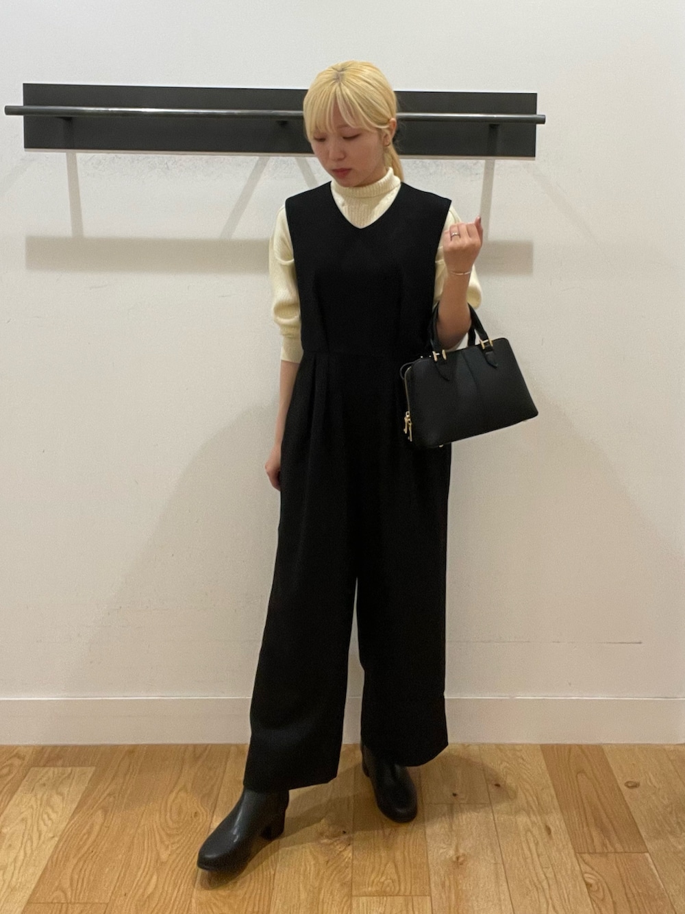 ブラック系のハンドバッグ、ブラック系のブーツ、ホワイト系のニット/セーターを着用したレディースの冬コーディネートの2枚目の写真