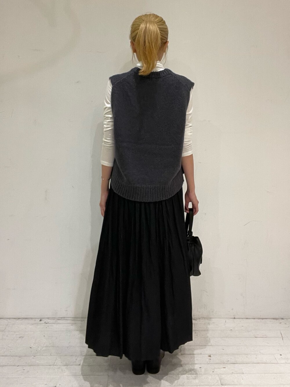 ブラック系のスカート、ブラック系のショルダーバッグ、ブラック系のブーツを着用したレディースの秋コーディネートの4枚目の写真