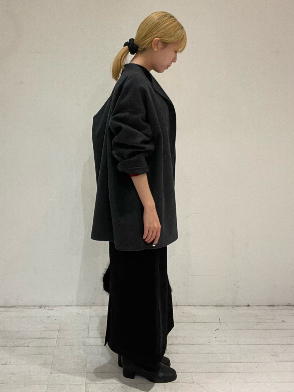 レッド系のニット/セーター、グレー系のその他アウター、ブラック系のスカートを着用したレディースの秋コーディネートの3枚目の写真