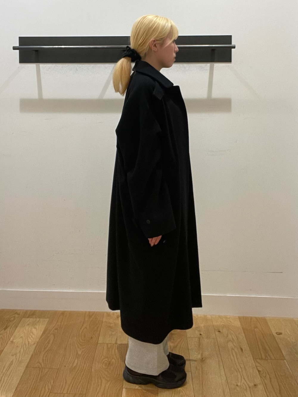 ブラック系のステンカラーコート、グレー系のニット/セーター、グレー系のその他パンツを着用したレディースの冬コーディネートの3枚目の写真