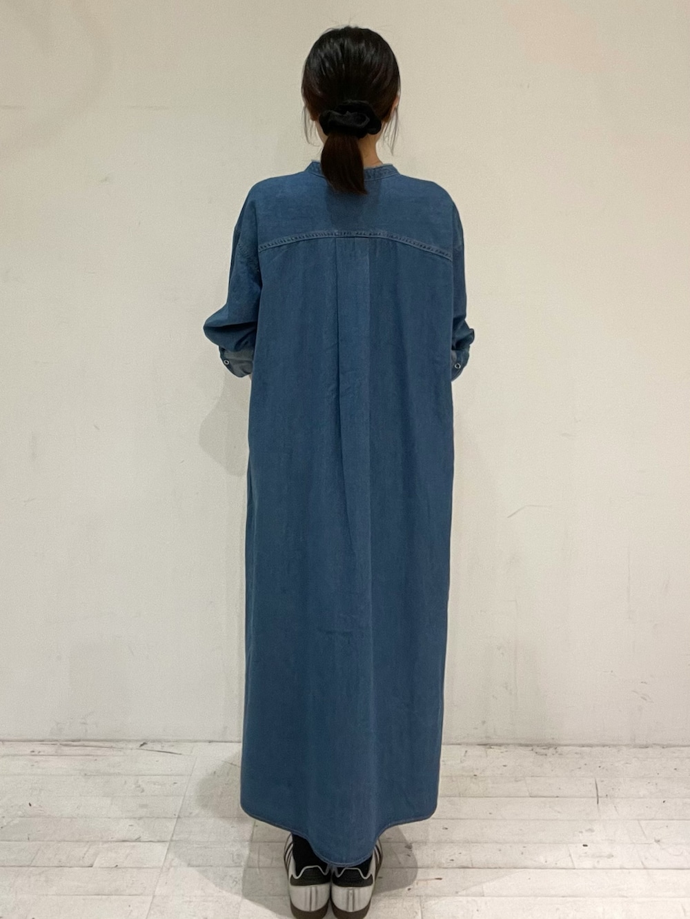 ブルー系のワンピース、ブラック系のショルダーバッグ、ホワイト系のスニーカーを着用したレディースの秋コーディネートの4枚目の写真