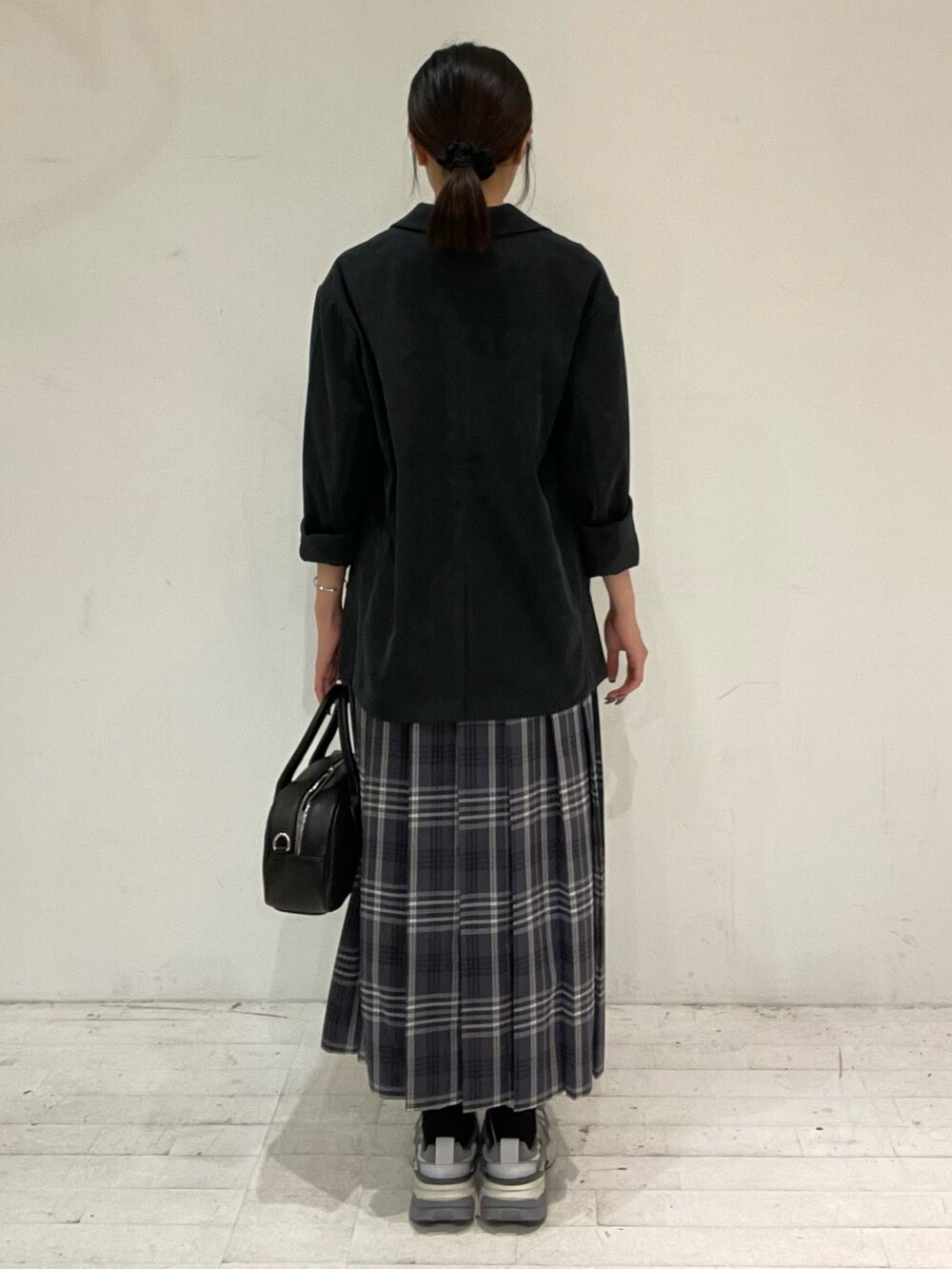 グレー系のスカート、ブラック系のショルダーバッグ、ホワイト系のTシャツ/カットソーを着用したレディースの秋コーディネートの4枚目の写真