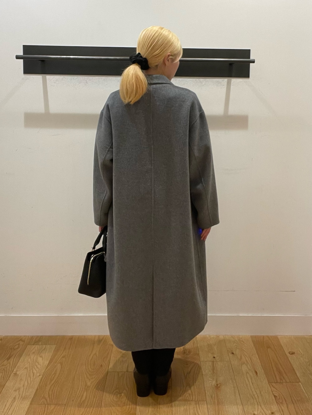 ブラック系のハンドバッグ、ブラック系のブーツ、ホワイト系のニット/セーターを着用したレディースの冬コーディネートの4枚目の写真