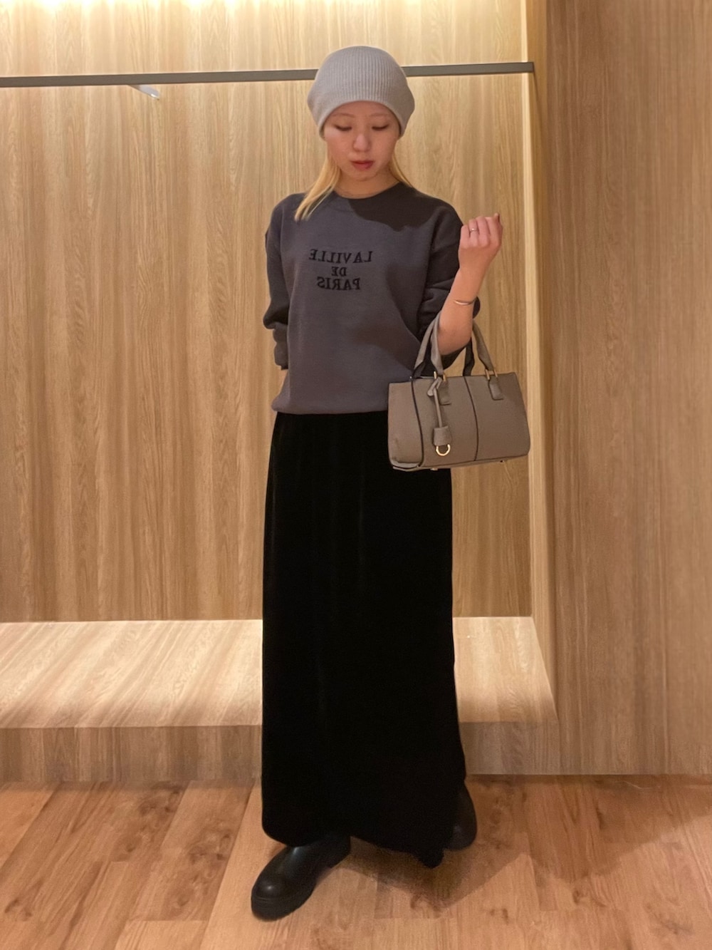 ブラック系のスカート、ブラック系のブーツ、グレー系のハンドバッグを着用したレディースの冬コーディネートの5枚目の写真