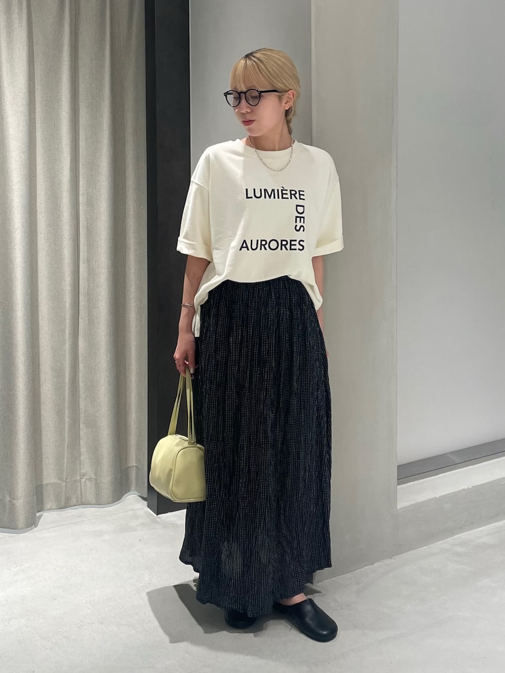 ブラック系のその他シューズ、ブラック系のスカート、ベージュ系のTシャツ/カットソーを着用したレディースの夏コーディネートの2枚目の写真